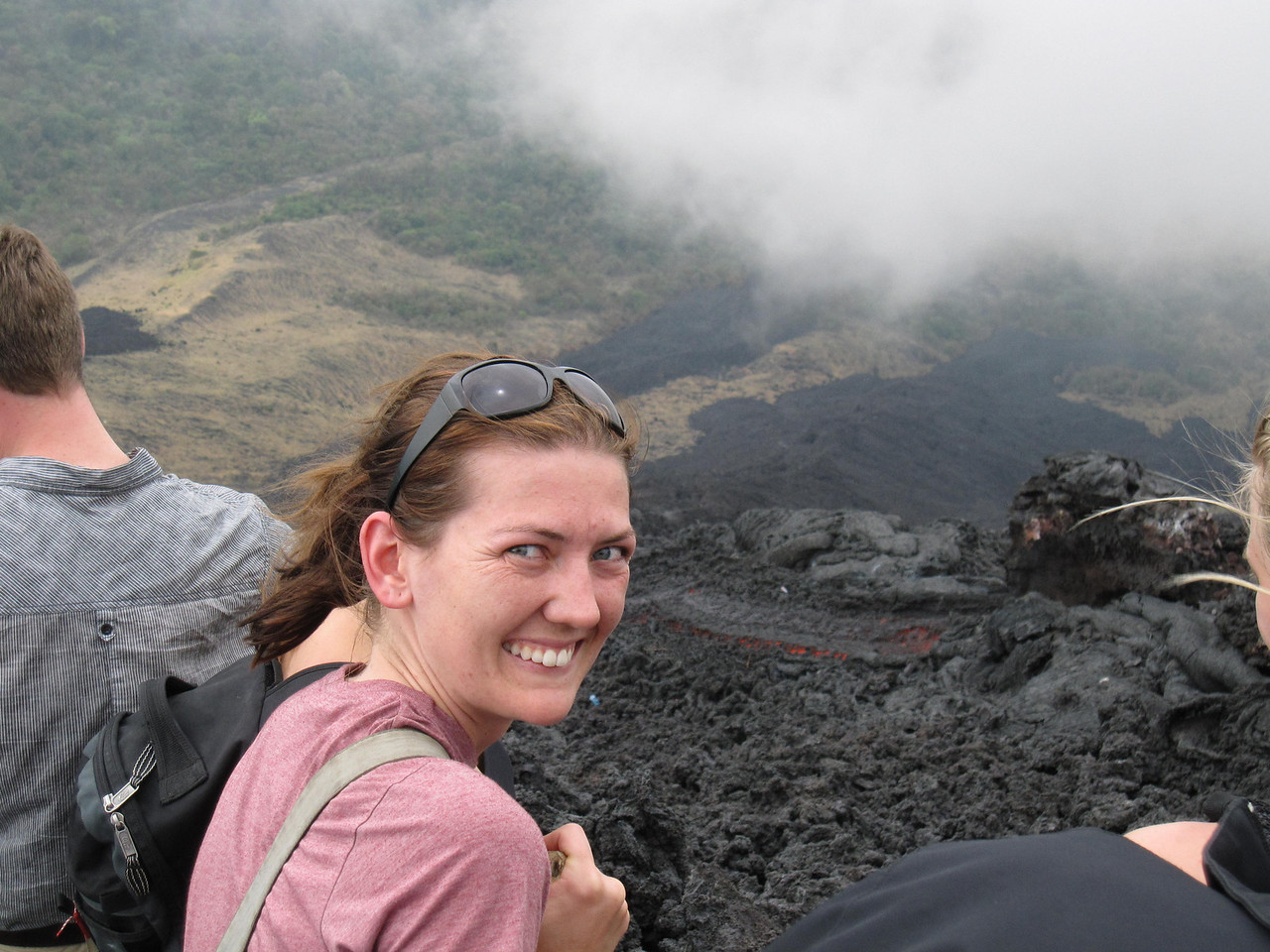 precariously perched on a ledge near pacaya volacano looking at the red hot lava flow