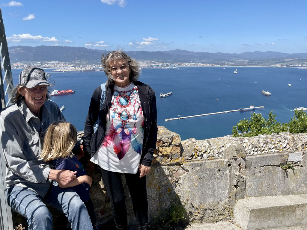 Two adults and a child standing on historic fortifications on the Rock of Gibraltar, overlooking the water below.