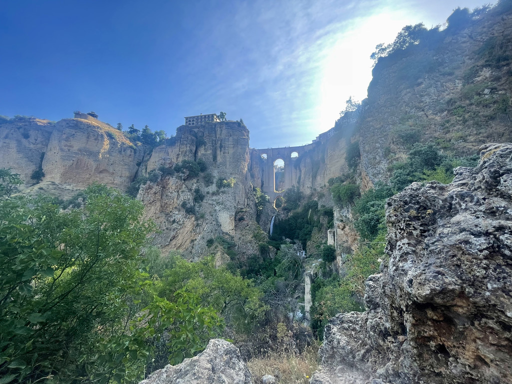Puente Nuevo bridge spanning El Tajo gorge in Ronda, Spain, with a waterfall below and a house on the clifftop.