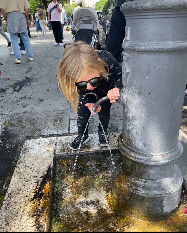child drinking from Rome public fountain in Rome.