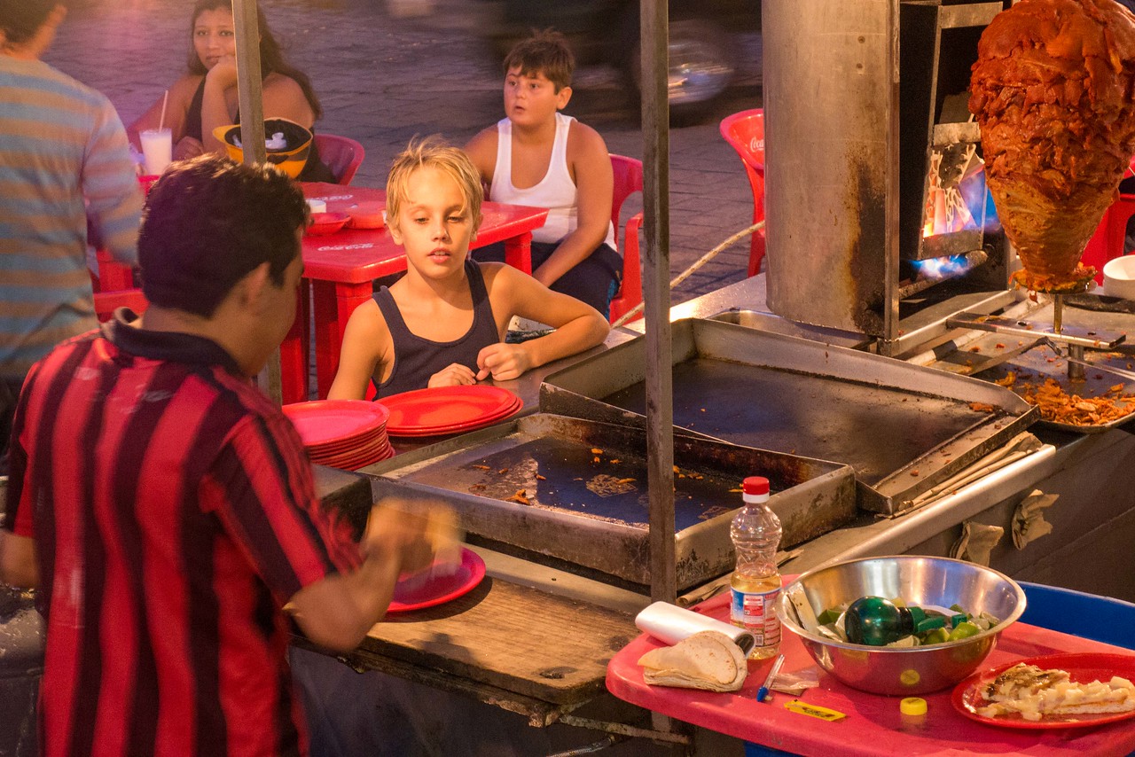 my nephew learning about other cultures as a child at a street food stall in mexico