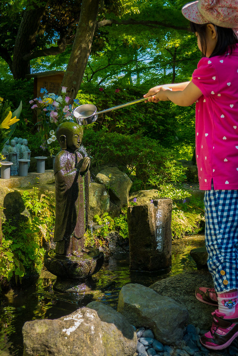 Jizō is a beloved and popular Japanese divinity known to alleviate the suffering of the living and the dead. Jizō is also the patron saint of travelers. I first encountered Jizō statues at the Garden of Unborn Children in Tokyo, and was intrigued to see this other representation. As I continued through Japan, I found thousands of representations of this Bodhisattva. At Hase-dera, the Japanese and foreigners alike patiently waited in line to ladle water from the trickling stream. This little girl watched her mother spoon the water and pour it in a cascade down the statue's body and carefully followed suit, insisting that she could perform the task and the little prayer on her own (she did). Little girl pours water