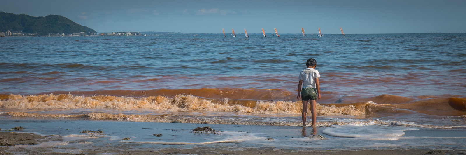 An algae growth in the water caused a red hue on Kamakura beach — but the kiddos didn't mind! Kamakura Beach with red tide algae