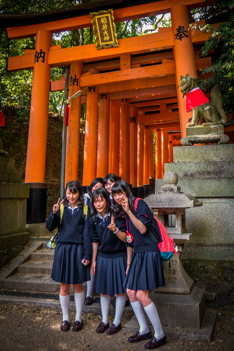 School girls pose at the iconic orange torii gates at Fushimi Inari Shrine school girls at Fushimi Inari Shrine