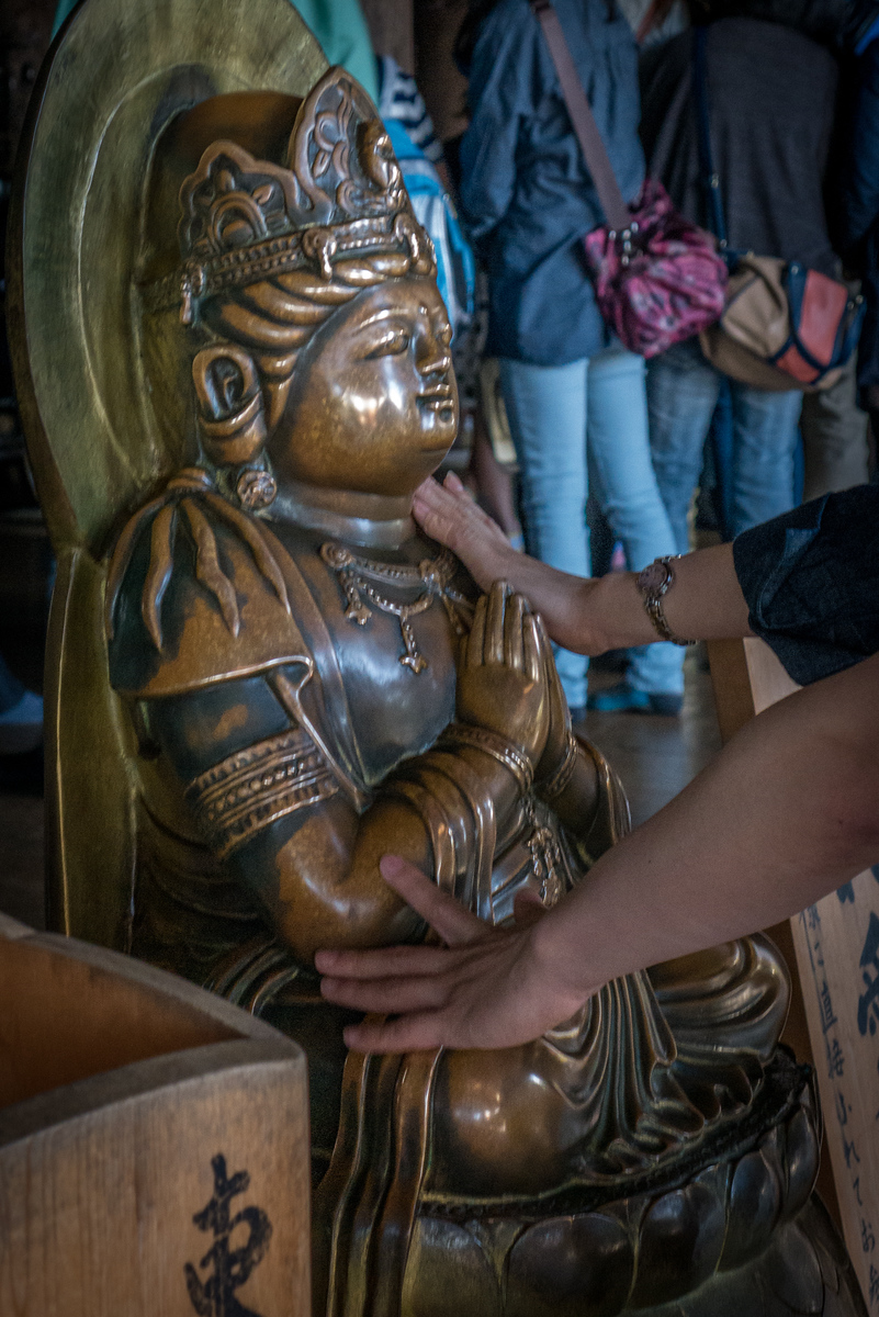 Rubbing for good luck, the statue is worn in many places around the knee and shoulders from decades of worshippers. statue at Kiyomizu-dera temple
