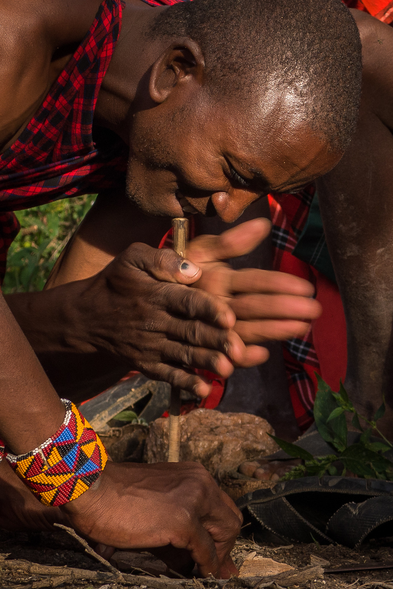 One of the Maasai warriors spinning a stick of wood between his hands to create enough friction to start our campfire for the night. One of the Maasai warriors spins the stick quickly to create friction!