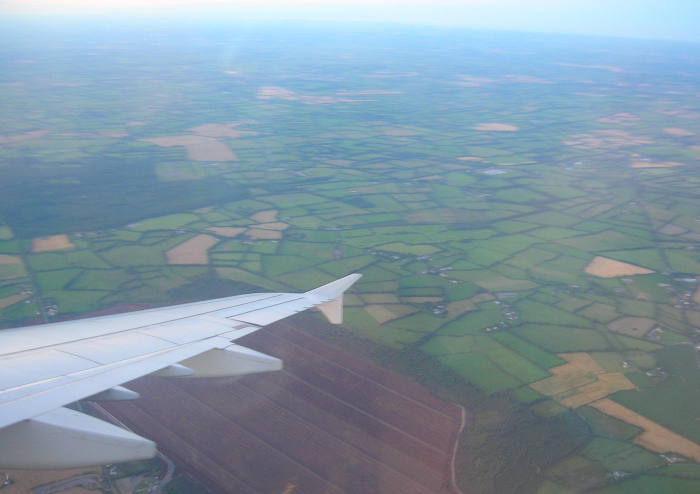 Using a travel app to prepare for my trip as I look out from the plane window over Ireland