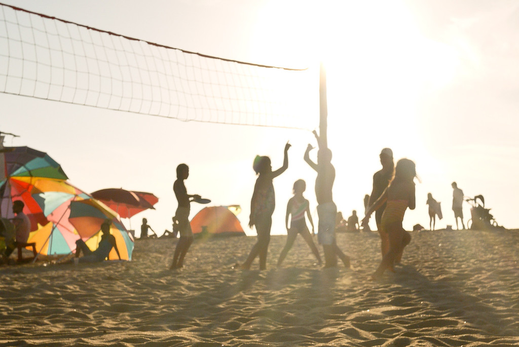 Group of kids playing beach volleyball.