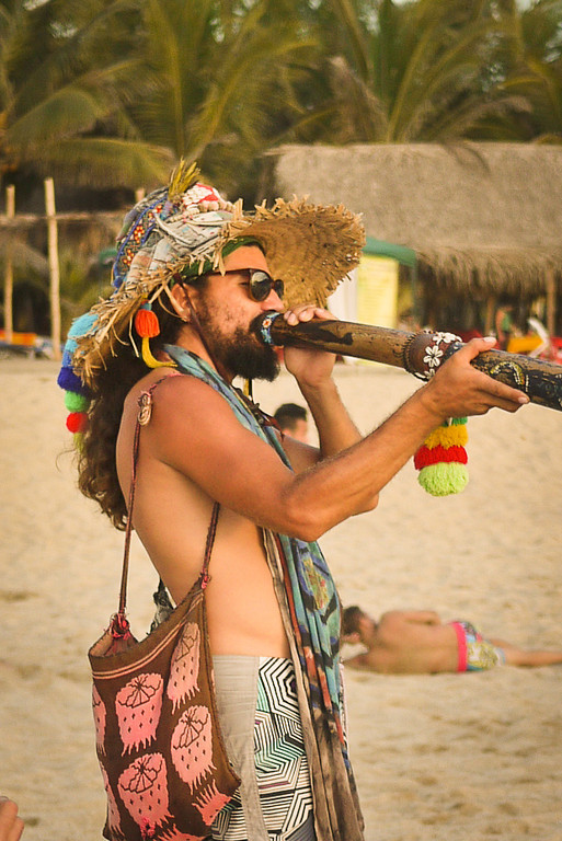 A man plays a didgeridoo on the beach." title="A man plays a didgeridoo on the beach.