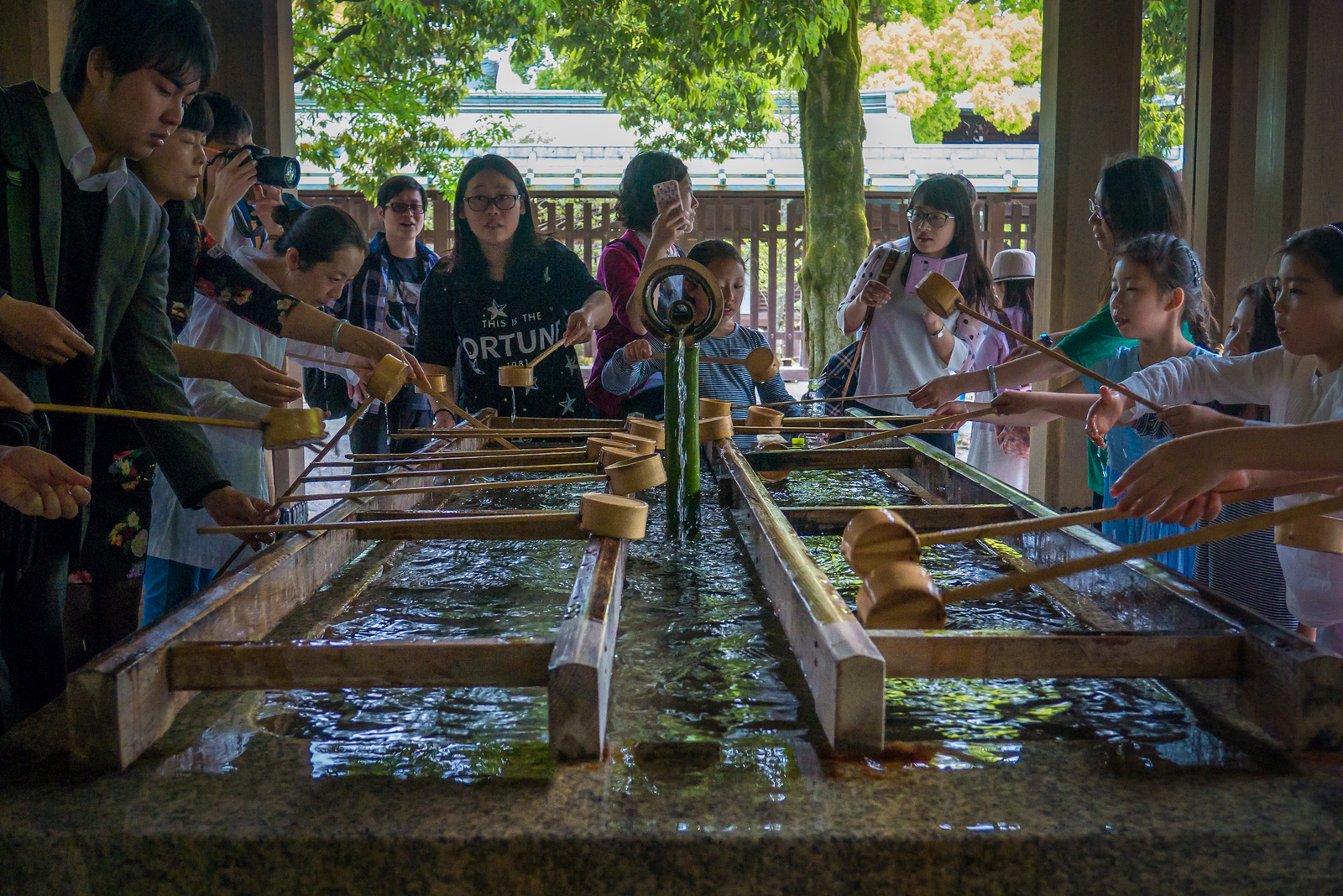 Visitors perform temizu at the ablution pavilion before entering Meiji Jingu, a shinto shrine in Shibuya, Japan Meiji Shrine religious hand washing