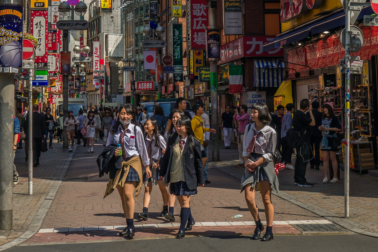 School girls cross the street in the colorful Shibuya District of Tokyo, Japan. shibuya japan