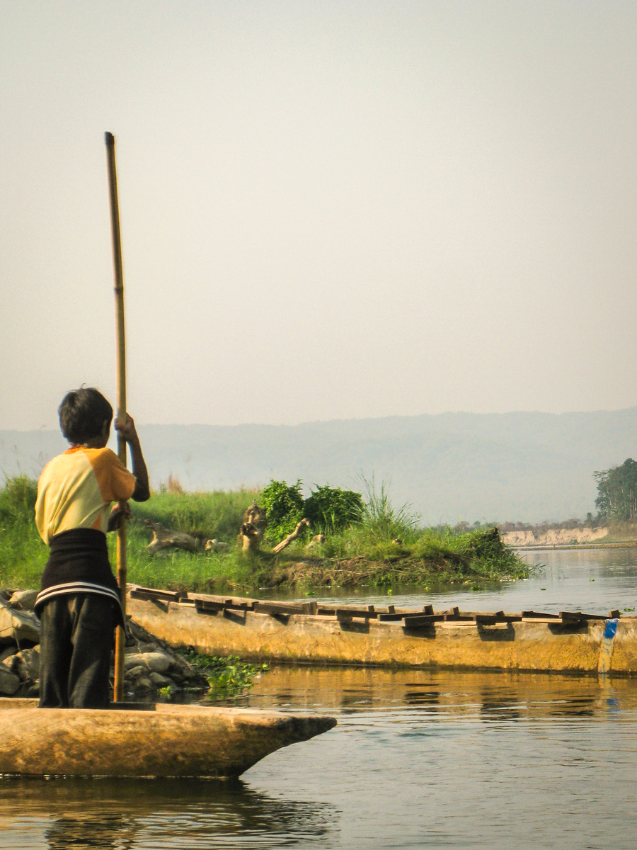 A boy in Chitwan National Park canoes through the river to his home in a Tharu village nearby. chitwan national park travel guide