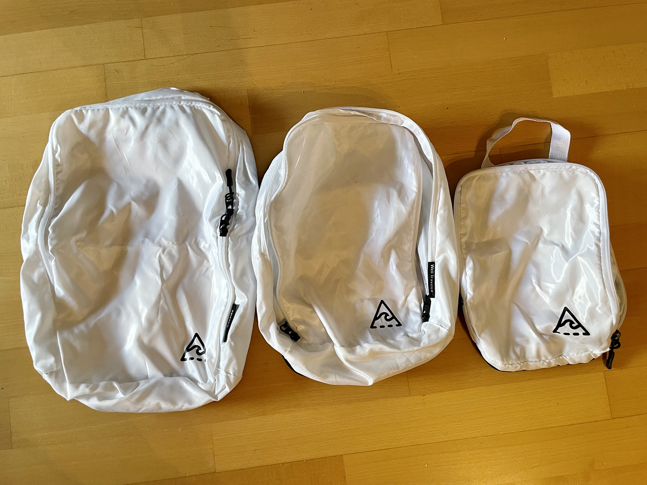 three well traveled packing cubes in various sizes, small, medium, and large