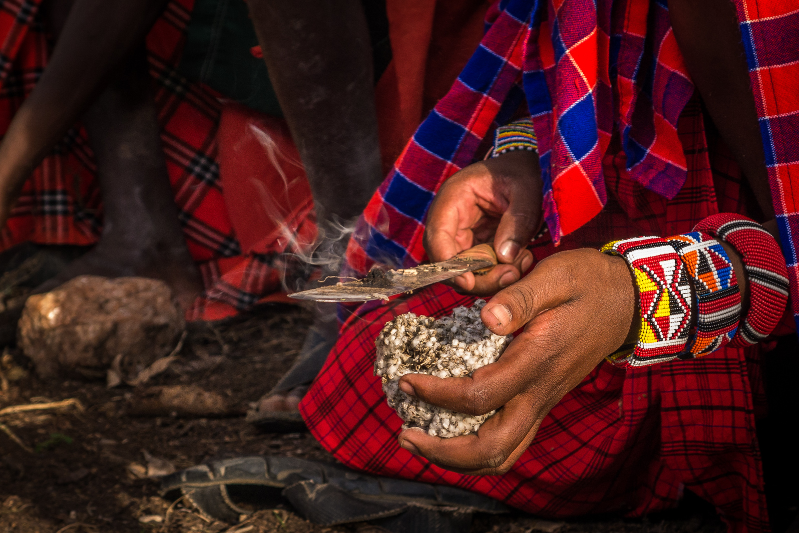 Salaton transfers the piece of smoldering into a waiting bundle to form the base of our campfire and to then light the pile of sticks and logs nearby. learning how to make a campfire