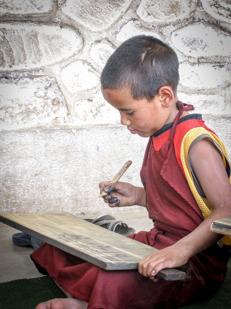 A young monk in training learns Tibetan script at a monastery in Pharping, Nepal. volunteering with monks in nepal