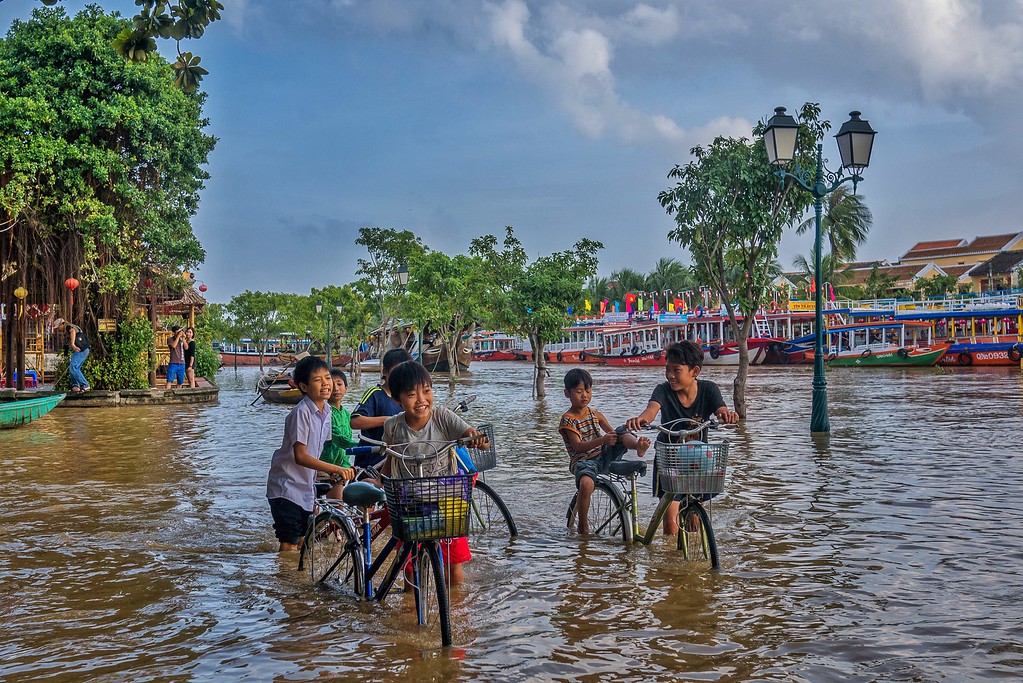 Local kids have a blast navigating through the flooded streets. responsible travel Hoi An, Vietnam.